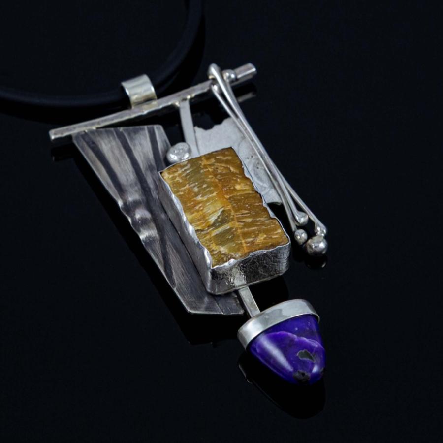 Photograph of an abstract silver pendant with a gold textured block and a small purple gem.