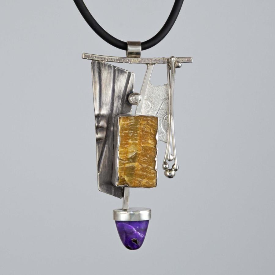 Photograph of a modern silver pendant with a textured gold rectangle and purple stone on a cord.