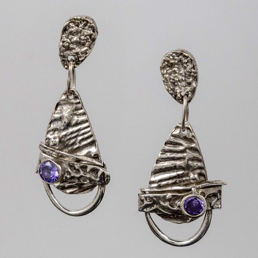 Photograph of textured silver drop earrings with small purple circular gemstones.