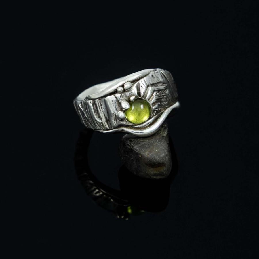 Silver ring with a small lime-green stone, centered against a black background.