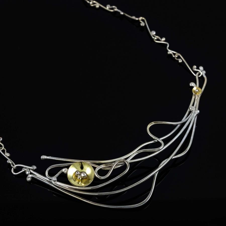 Photograph of a silver and gold wire-style necklace with a small orb pendant on a black background.