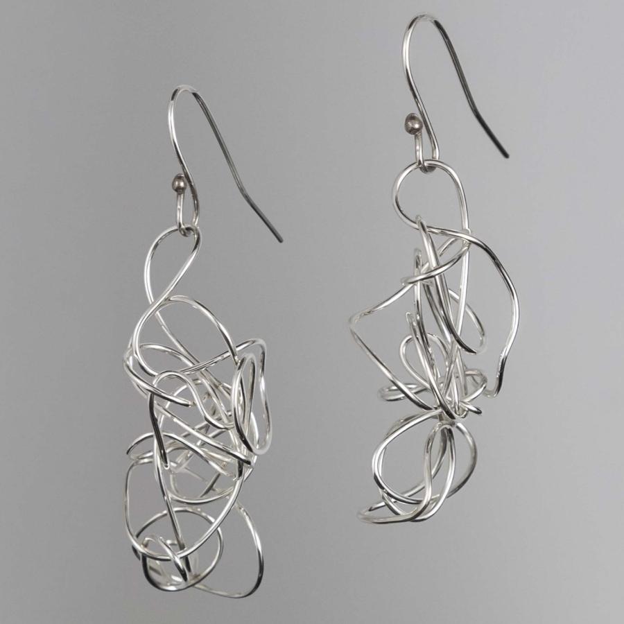 Photograph of two silver drop earrings featuring abstract, tangled wire designs.