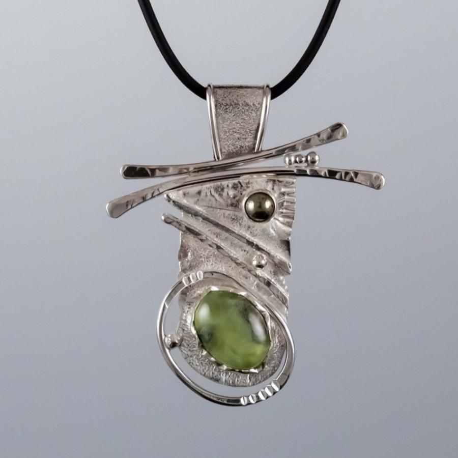 Photograph of a handcrafted silver pendant with a green stone on a black cord.