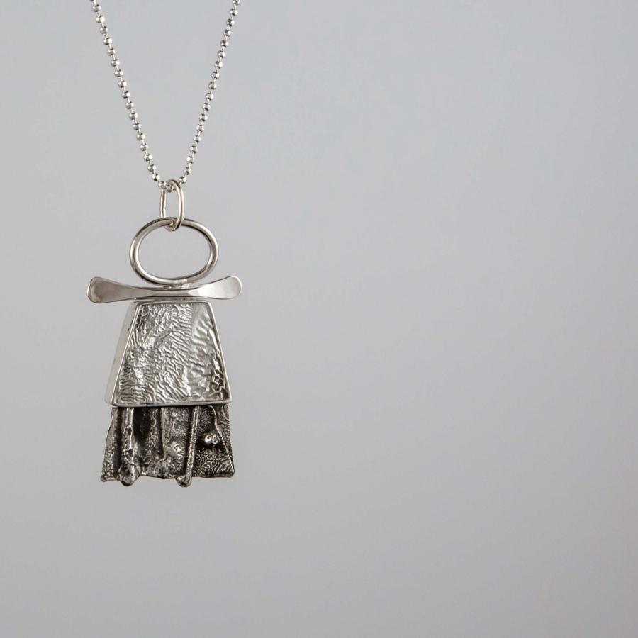 Photograph of a textured silver pendant on a thin silver chain.