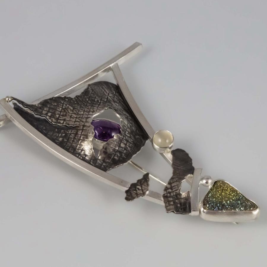 Photograph of a contemporary sterling silver brooch featuring amethyst and multi-colored stones.