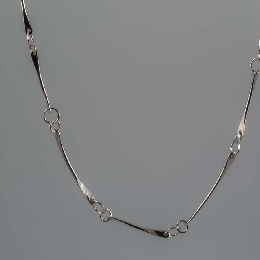 Photograph of a long, delicate silver chain necklace on a gray background.