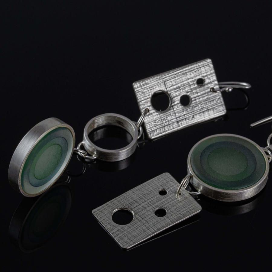 Photograph of two drop earrings featuring textured metal rectangles, silver rings, and green glass discs.