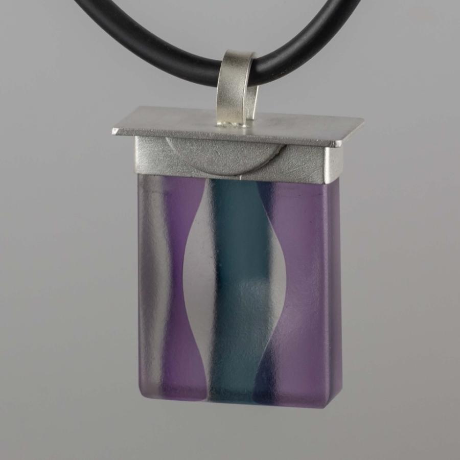 Photograph of a rectangular, purple and blue glass pendant on a black cord.