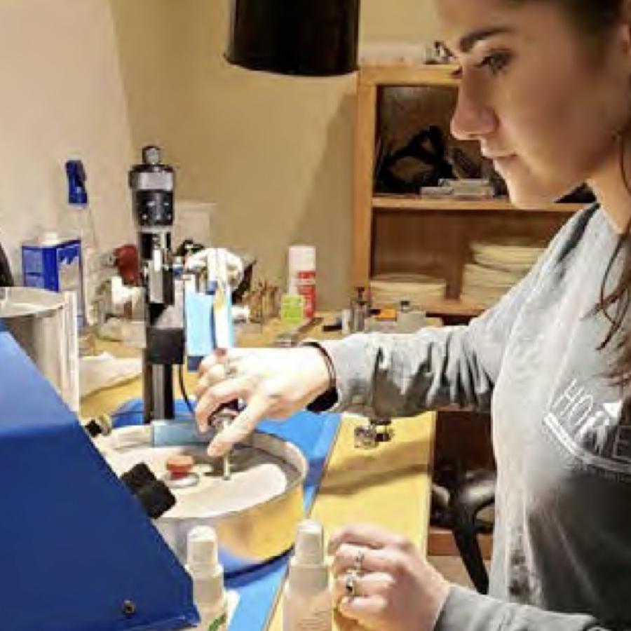 Photograph of a woman using a rotary tool in a workshop.