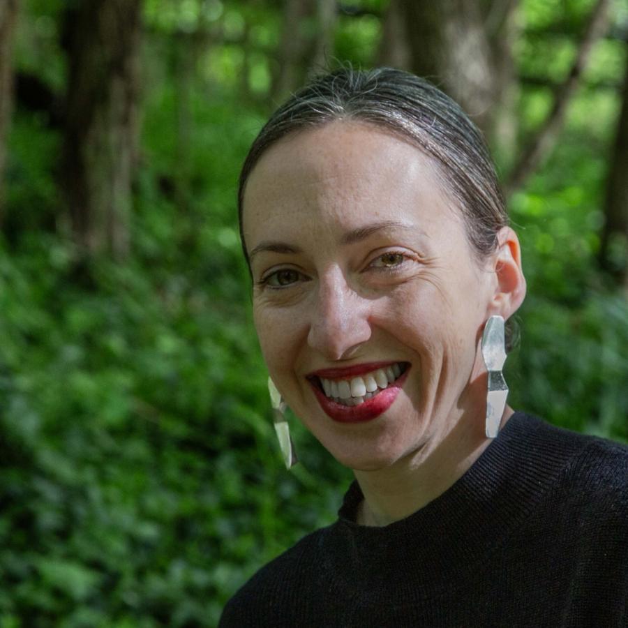 Photograph of a smiling woman in a lush green forest.