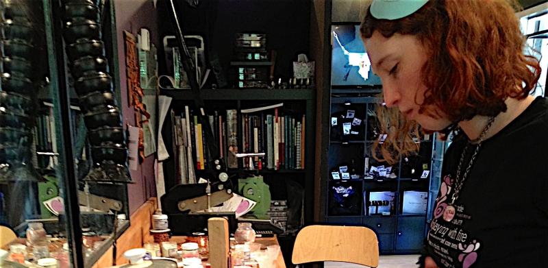 A jeweler works with a soldering torch at a wooden workbench.