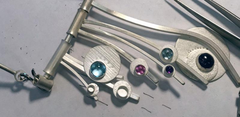 piece with hanging strands of silver wire and blue and pink stones set on discs