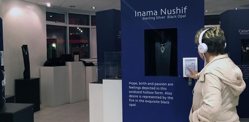 Person at jewelry exhibit wearing headphones.