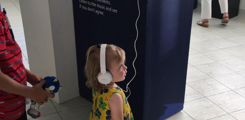 Child wearing headphones looking at exhibit.