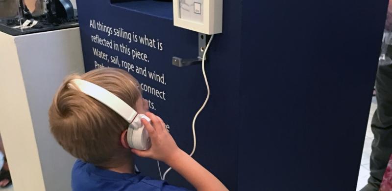 Boy with headphones listens to exhibit.