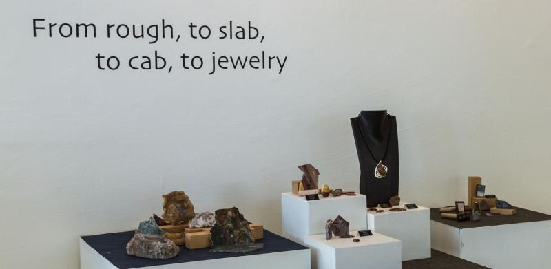 Jewelry display on white shelves with rough rocks.