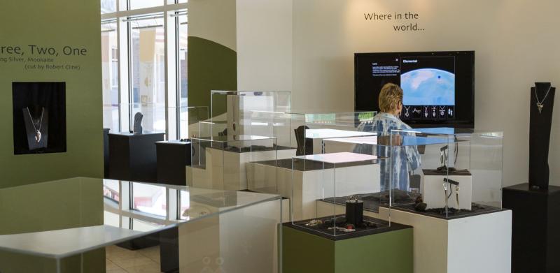 Jewelry display with cases on white and green pedestals.