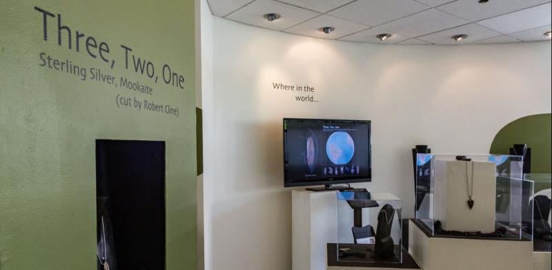 Gallery exhibit of jewelry displayed on stands.
