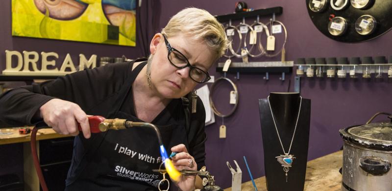 Woman making jewelry with a torch