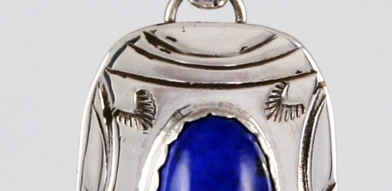 A silver pendant with a blue stone