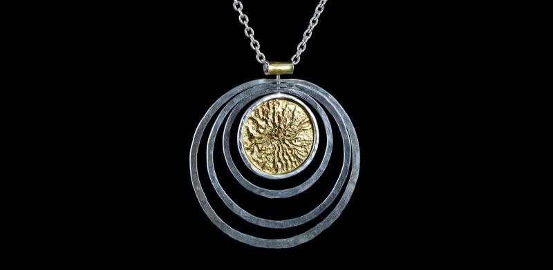 A silver pendant with gold accents
