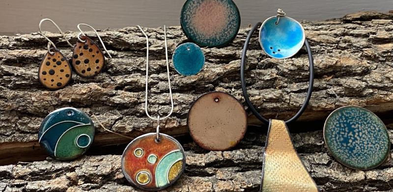 Several enameled pieces of jewelry on a wood background