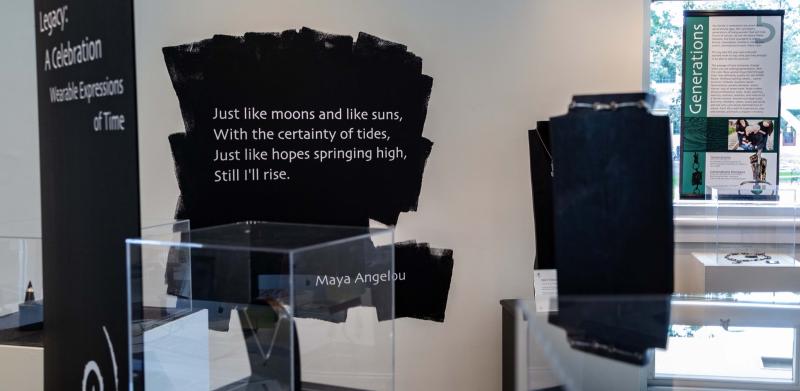 Museum display with Maya Angelou poem text on wall above a jewelry case.