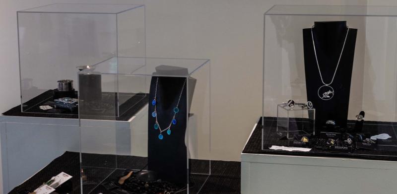 SilverWorks jewelry exhibition with faculty name list and necklaces displayed in glass cases.