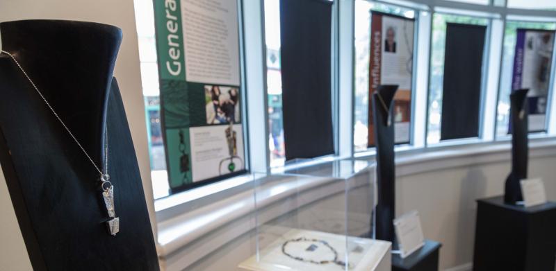 Museum display featuring jewelry on black stands and in glass cases with informational posters.