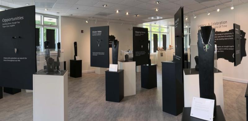 Panoramic view of an exhibition featuring jewelry displayed on pedestals.