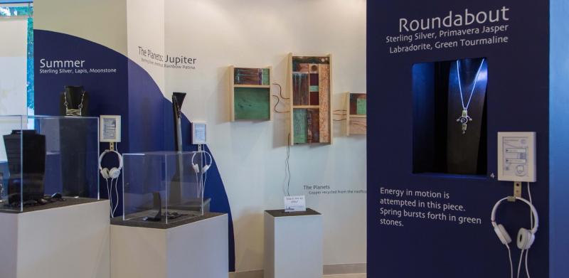 Photograph of a museum exhibit featuring jewelry displays with informational text and headphones.
