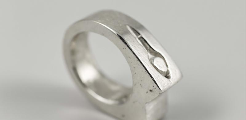 Photograph of a silver ring with a carved design.