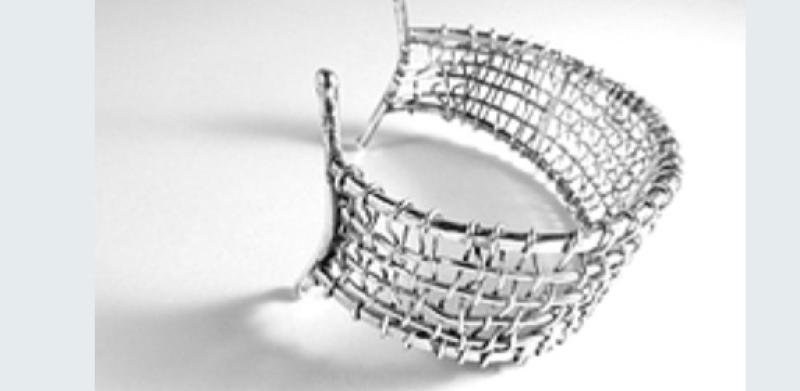 Photograph of a silver-toned, wire-mesh cuff bracelet on a white background.