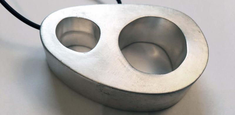 Photograph of a silver-toned metal pendant with two unequal holes on a black cord.