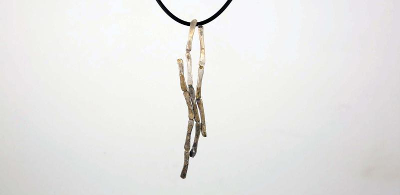 Photograph of a long, metallic, abstract branch pendant on a thin black cord.