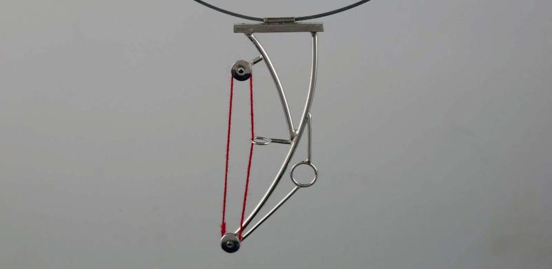 Minimalist silver wire necklace with a red looped accent and geometric details.
