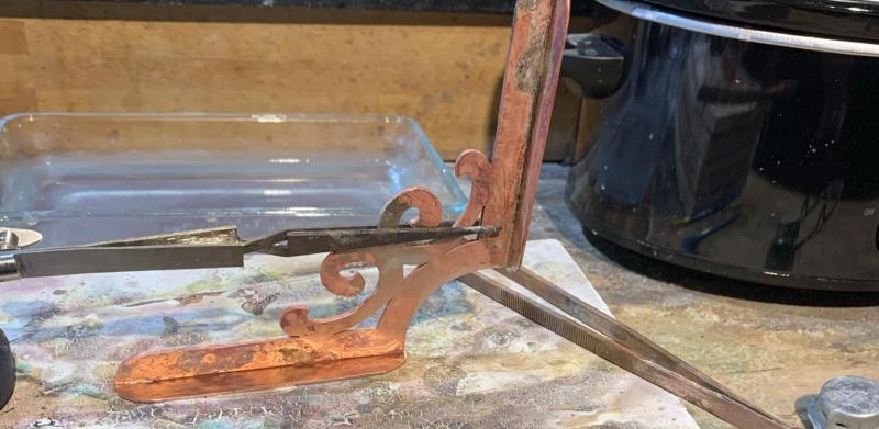 Photograph of a metalworking tool clamped to a stack of tiles on a workbench.