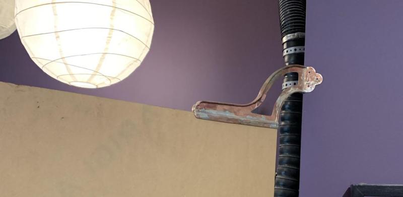 A copper jewelry piece resting on a wooden partition under a round paper lantern.
