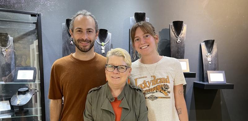 Photograph of three people posing in a jewelry store.