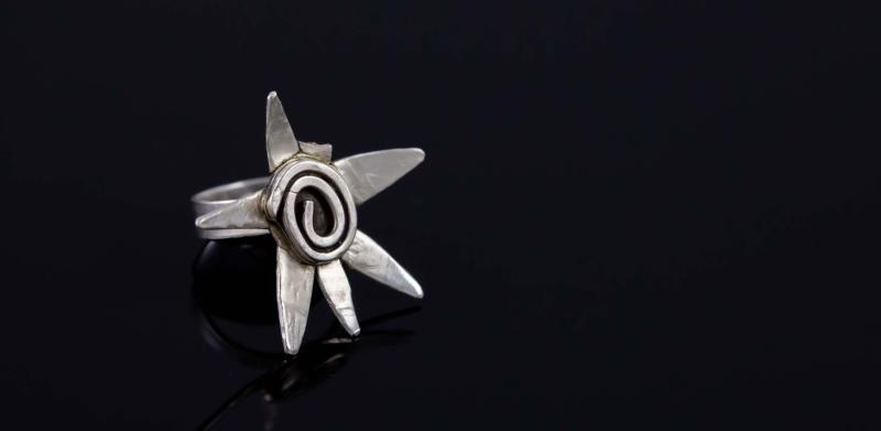 Photograph of a silver star-shaped ring on a black surface.