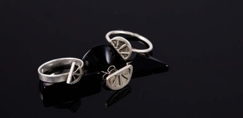 Photograph of three silver rings with half-circle designs on a dark, reflective surface.