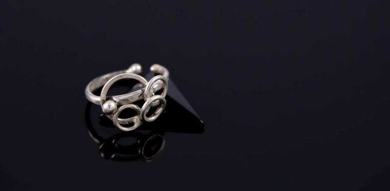 Photograph of a silver ring on a dark reflective surface.