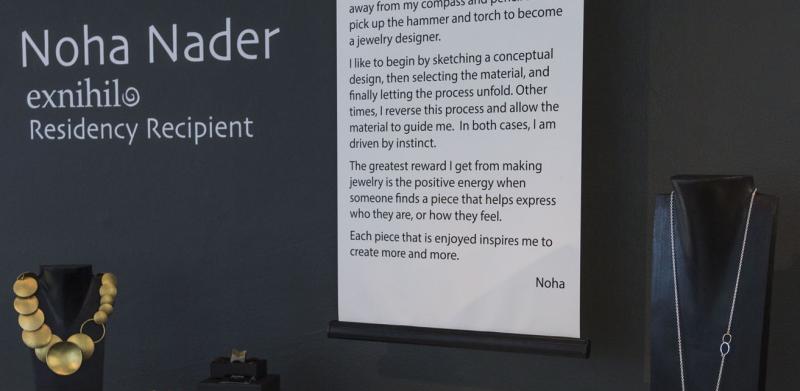 A jewelry exhibition display by Noha Nader featuring artist statements and necklaces.