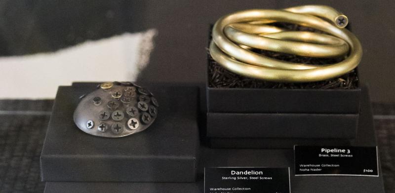 Photograph of metal jewelry pieces displayed in black boxes with labels.