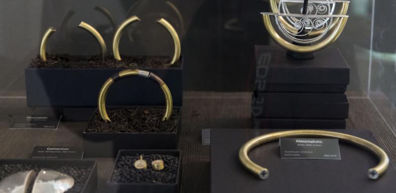 Gold and silver jewelry displayed in black boxes in a glass case.