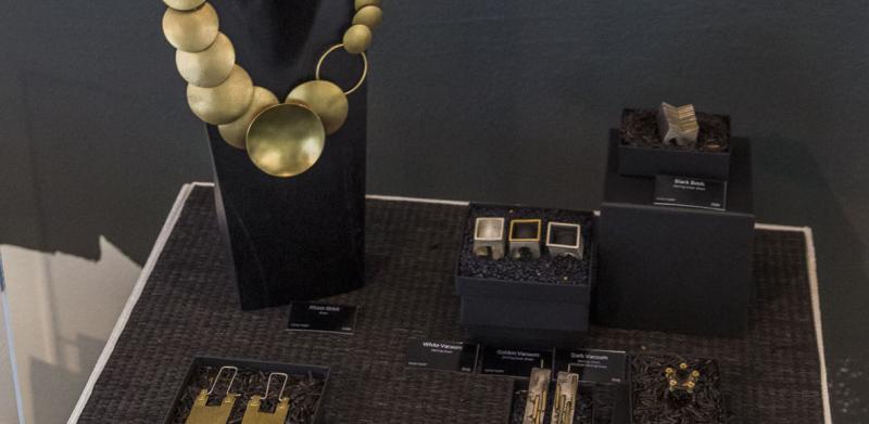 A display of jewelry by Noha Nader featuring gold necklaces and earrings.