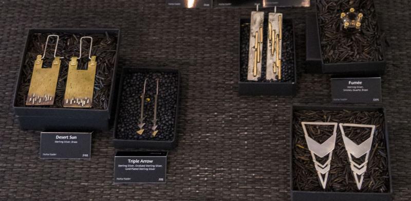 Display of unique jewelry pieces, including a large gold necklace and various earrings in boxes.
