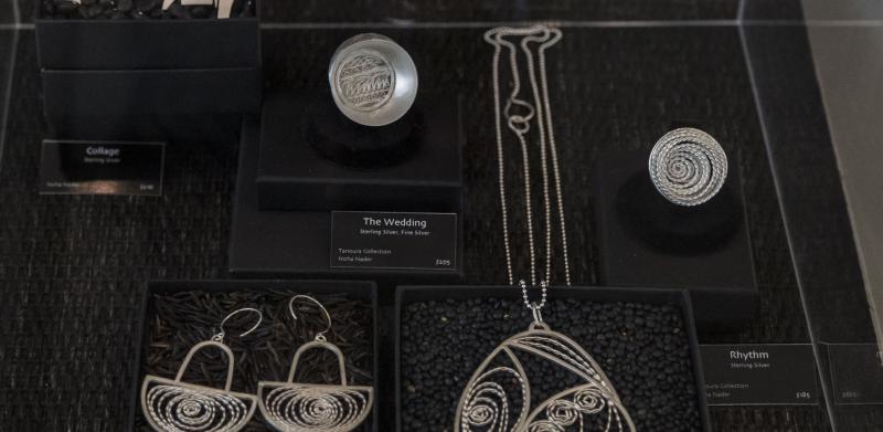 Display case with handmade silver jewelry pieces including earrings and necklaces.