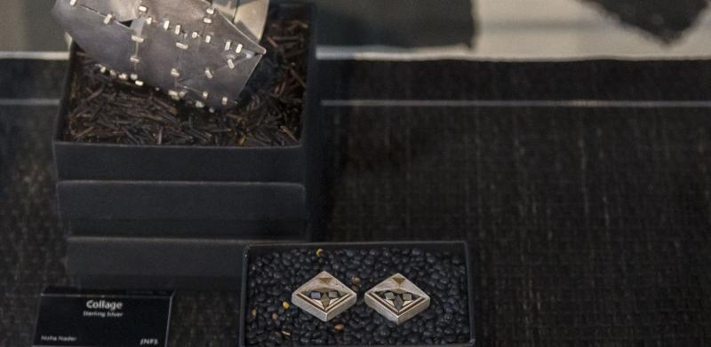 Photograph of jewelry on display with dark boxes and labels.