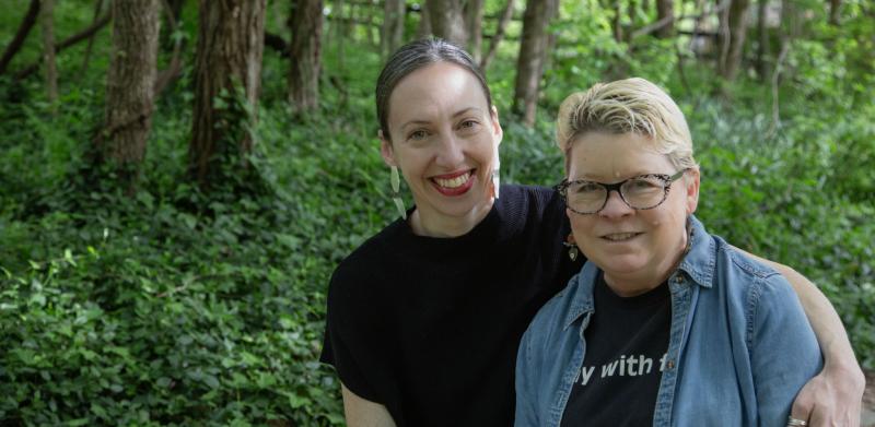 Photograph of two women smiling together in a lush green forest.